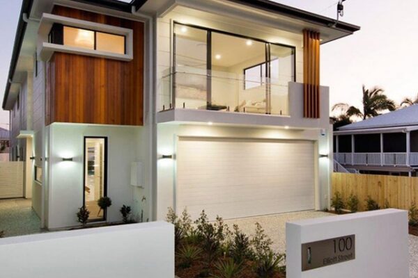 Stunning custom-built home with a stylish architectural design, featuring a glass-enclosed balcony, warm wood panelling, and a sophisticated entrance.