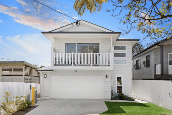 Modern two-story custom-built home with a white façade, large balcony, and double garage, designed by expert custom home builders for contemporary living.