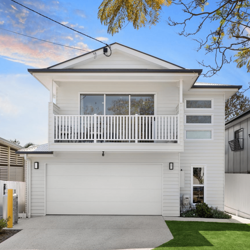 Modern two-story custom-built home with a white façade, large balcony, and double garage, designed by expert custom home builders for contemporary living.