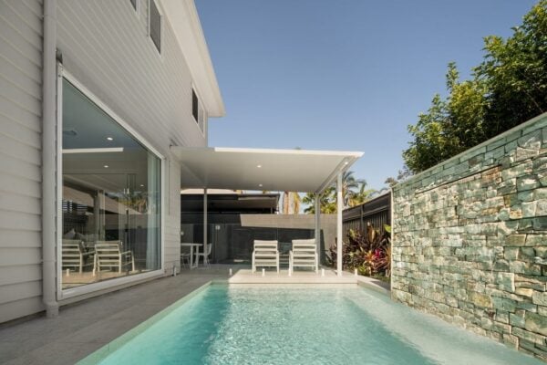 Luxury outdoor renovation in Brisbane featuring a modern pool, stone water feature, and covered alfresco area. Jensen Constructions specialises in custom home transformations for stylish outdoor living.