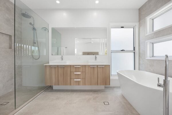 Luxury bathroom renovation in Brisbane by Jensen Constructions. Featuring a modern freestanding bathtub, glass walk-in shower, floating double vanity, and sleek neutral finishes for a spa-like retreat.