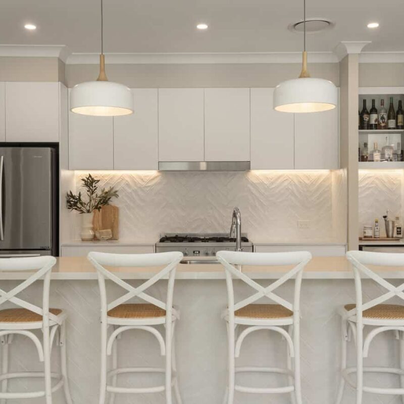 Bright and inviting kitchen with a neutral colour scheme, built-in bar area, and stylish pendant lights. Jensen Constructions enhances Brisbane homes with high-quality kitchen remodels.
